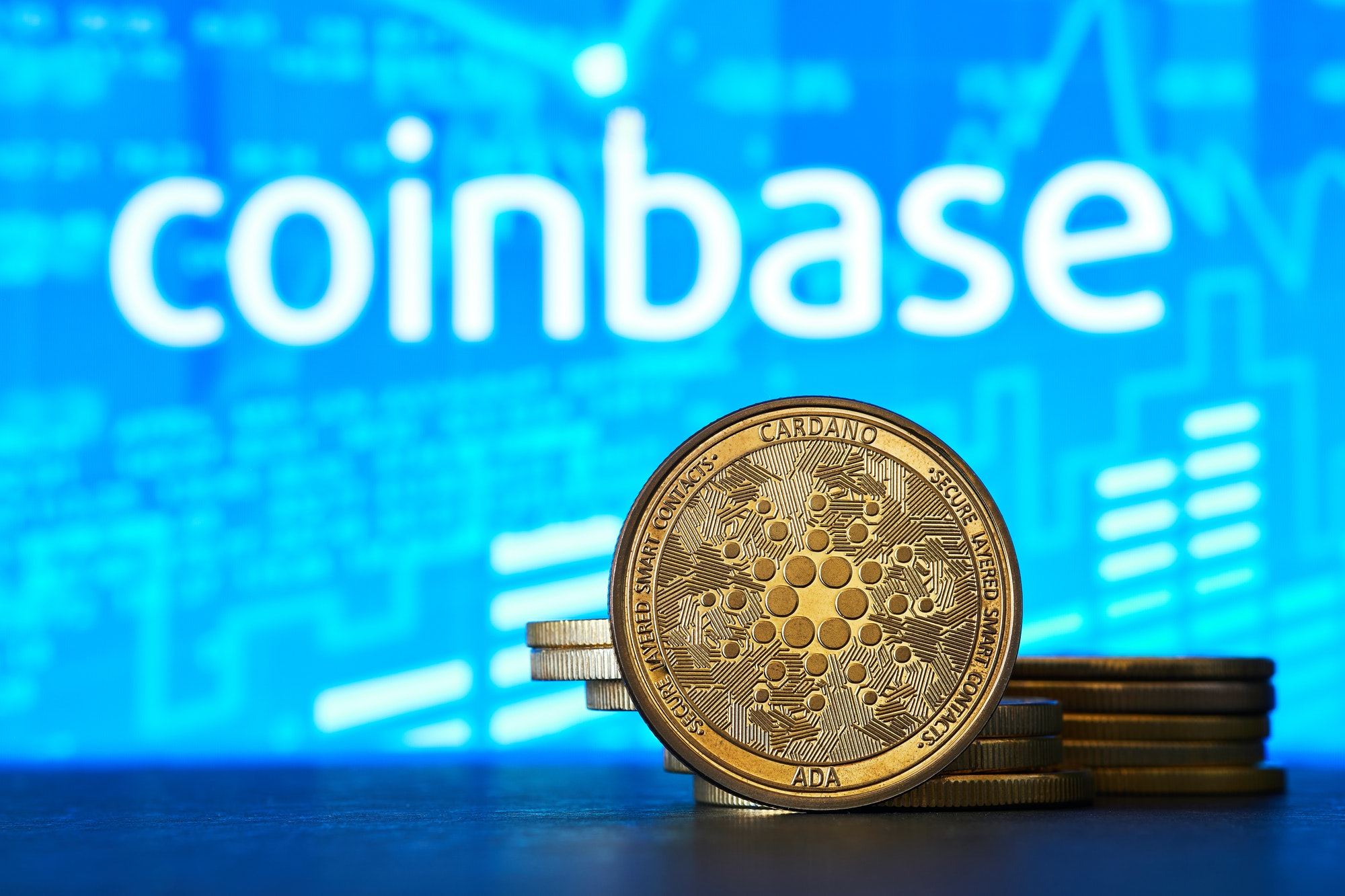 Coinbase logo on a computer screen with a stack of crypto coins